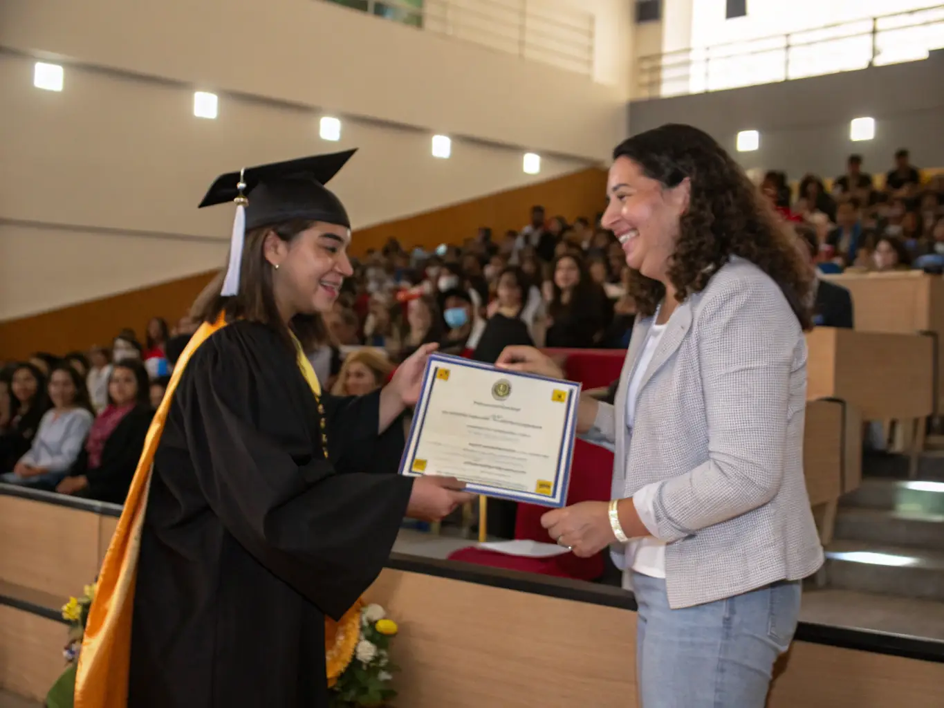 A photograph of a student receiving an award or certificate, with instructors and classmates applauding in the background. The image should convey a sense of accomplishment, recognition, and community support.